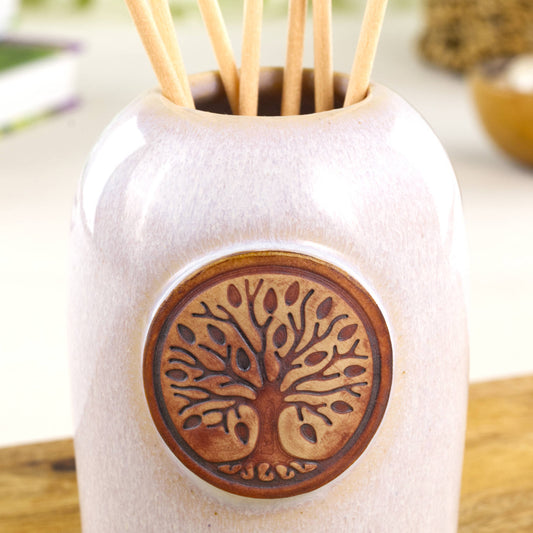 Close up of white pottery reed diffuser with Tree of Life detail and soft speckled glaze finish