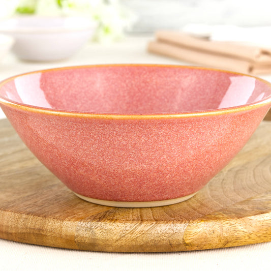 Close-up of a wheel-thrown stoneware bowl in Coral, showing the warm peachy glaze tones, glossy speckled finish and handcrafted pottery texture from a British studio