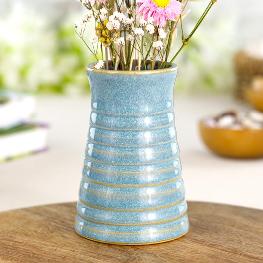 Hand thrown coastal blue ribbed ceramic bud vase on wooden board in Sea Smoothed Pebble glaze. Carved lines.