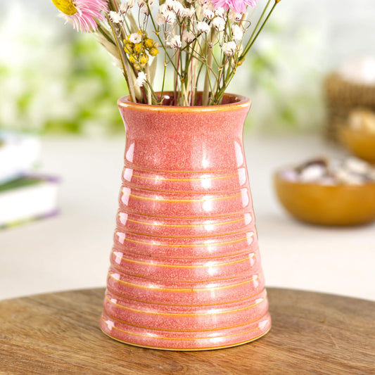 Coral ribbed ceramic bud vase displayed on a wooden board, ideal as a colourful shelf décor accent.