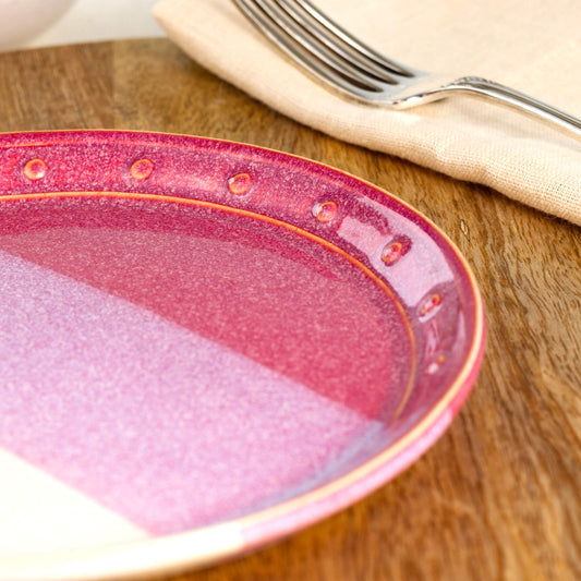 Close-up of a Crimson & White ceramic small plate, highlighting the glossy speckled glaze, hand-finished dotted rim and rich red glaze tones