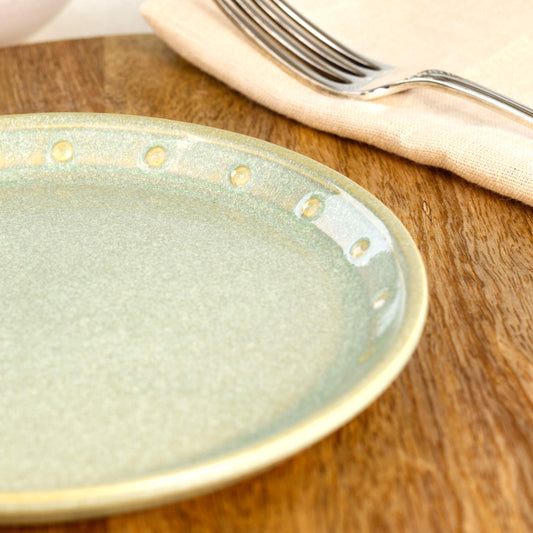 Close-up of a Pale Green ceramic small plate, highlighting the glossy speckled glaze, hand-finished dotted rim and soft green stoneware finish