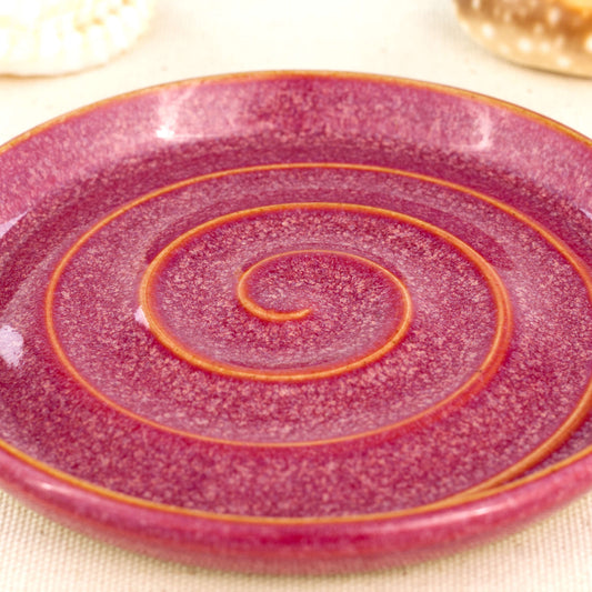 Close up of crimson glazed ceramic soap dish with spiral pattern and signature Sea Smoothed Pebble glaze.