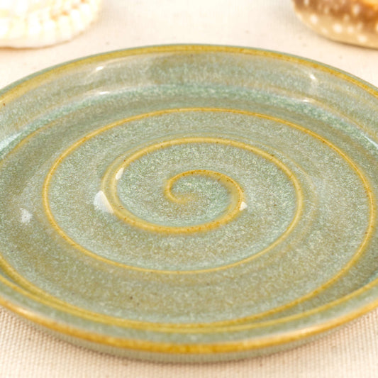 Close up of pale green glazed stoneware soap dish with spiral detail and signature Sea Smoothed Pebble glaze.