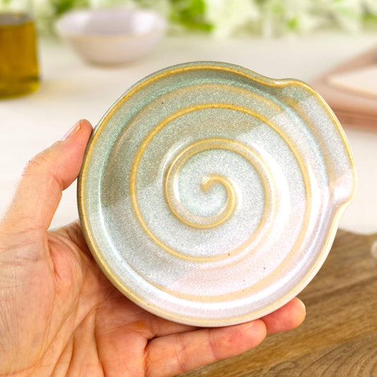 Pale Green and White pottery spoon rest shown in hand, compact handmade kitchen spoon holder for hob side cooking