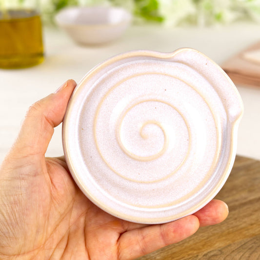 White handmade spoon rest shown in hand, compact wheel-thrown ceramic utensil rest in neutral tones for cottagecore kitchens