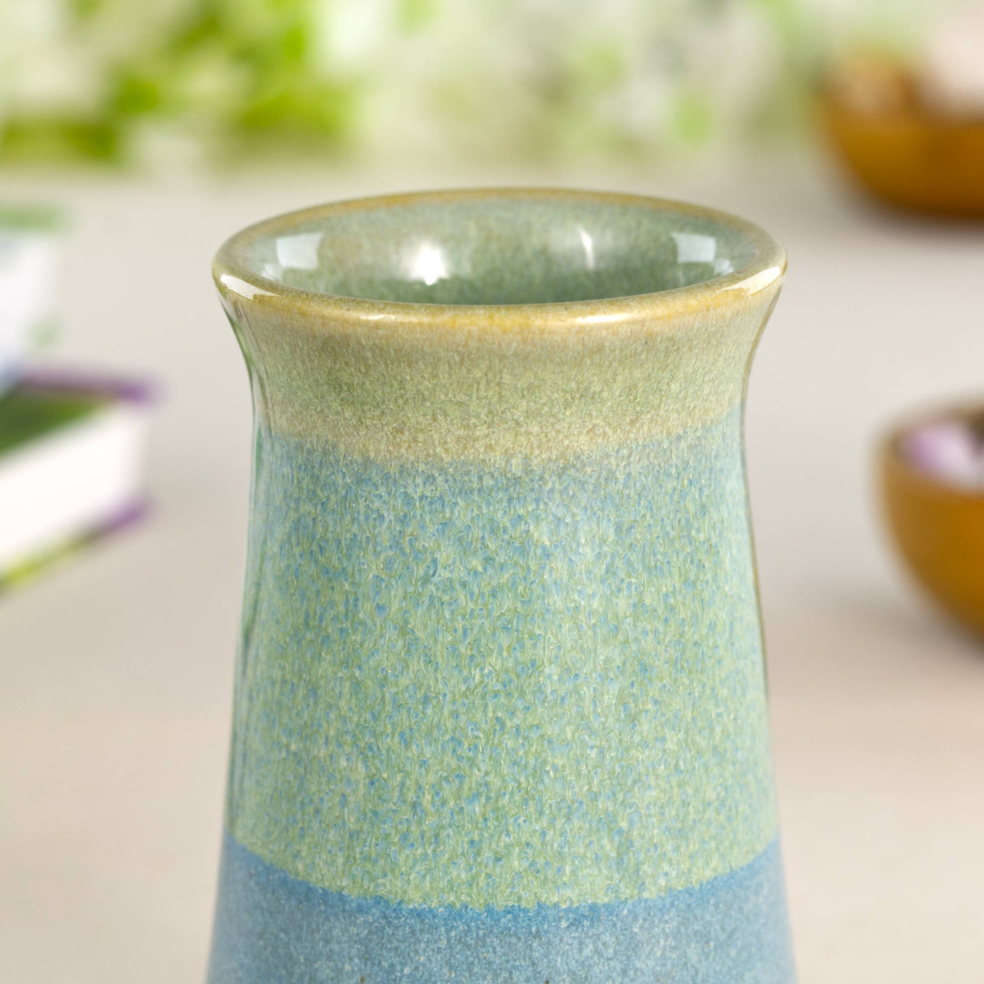 Artisan stoneware bud vase featuring layered coastal blue and soft pale green glazes, a textured glaze flow, and calming pastel hues.