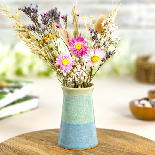 Handmade coastal blue and pale green bud vase filled with vibrant dried flowers, a decorative pastel ceramic accent perfect for brightening shelves and tabletops.