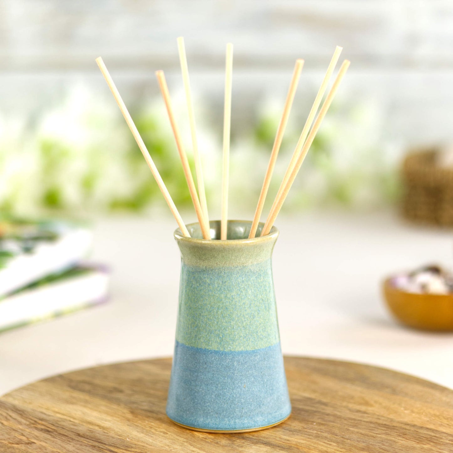 Tapered stoneware bud vase in layered coastal blue and pale green glazes, styled as a minimalist ceramic reed diffuser with a naturally textured finish.