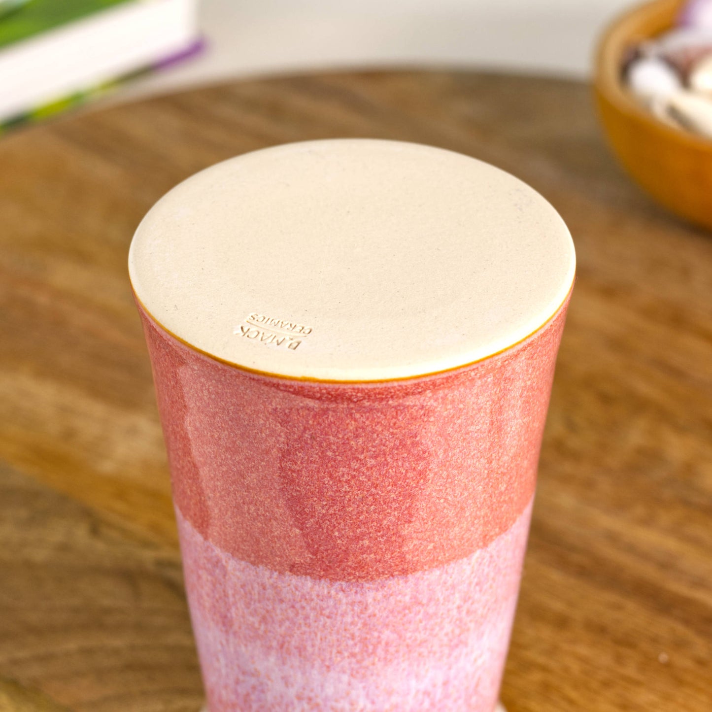 Burnished smooth base of a handmade coral and white stoneware bud vase, wheel-thrown conical pottery with a double-dipped layered glaze.