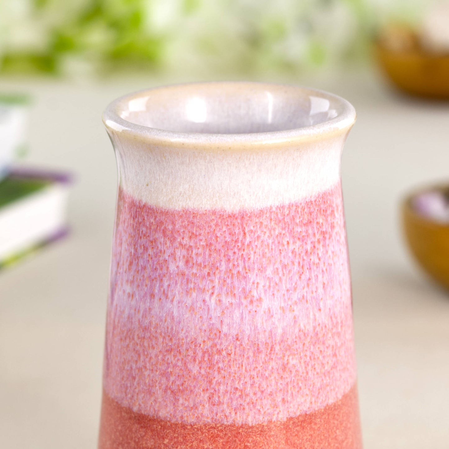 Close-up of a coral and white double-dipped ceramic bud vase featuring banded glazes in blush pink and pastel orange tones.