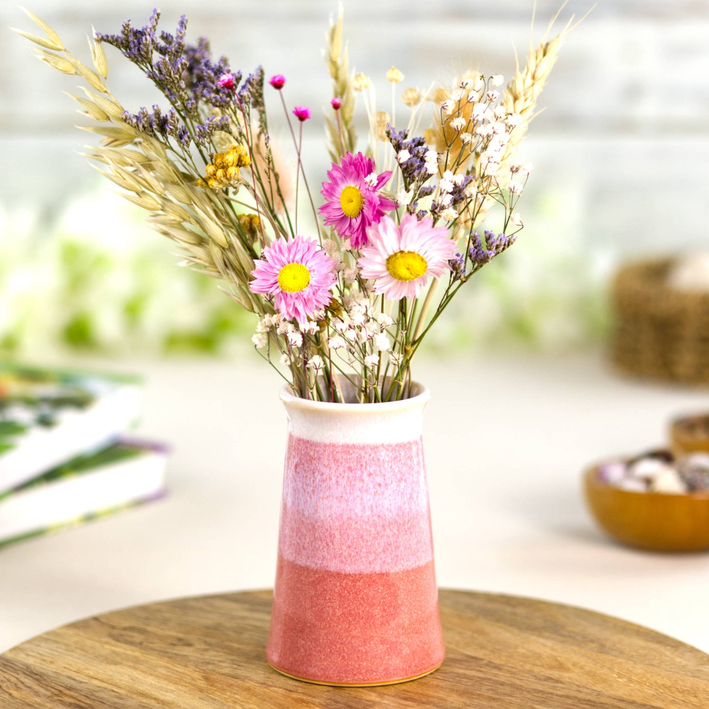 Handmade coral and white ceramic bud vase with colourful dried flowers, a banded double-dipped design in soft orange-pink hues.