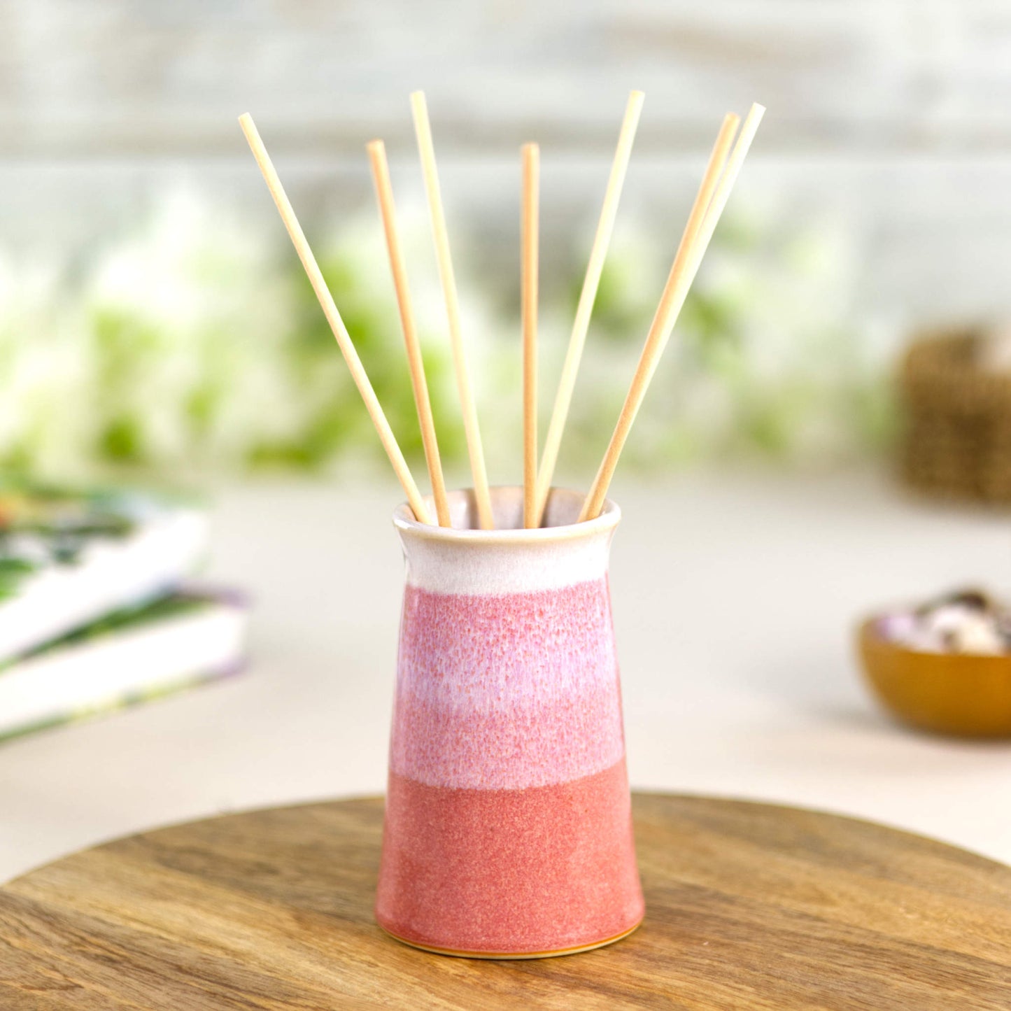 Coral and white stoneware bud vase styled as a reed diffuser, wheel-thrown tapered pottery with layered glazes.