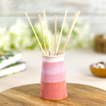 Coral and white stoneware bud vase styled as a reed diffuser, wheel-thrown tapered pottery with layered glazes.