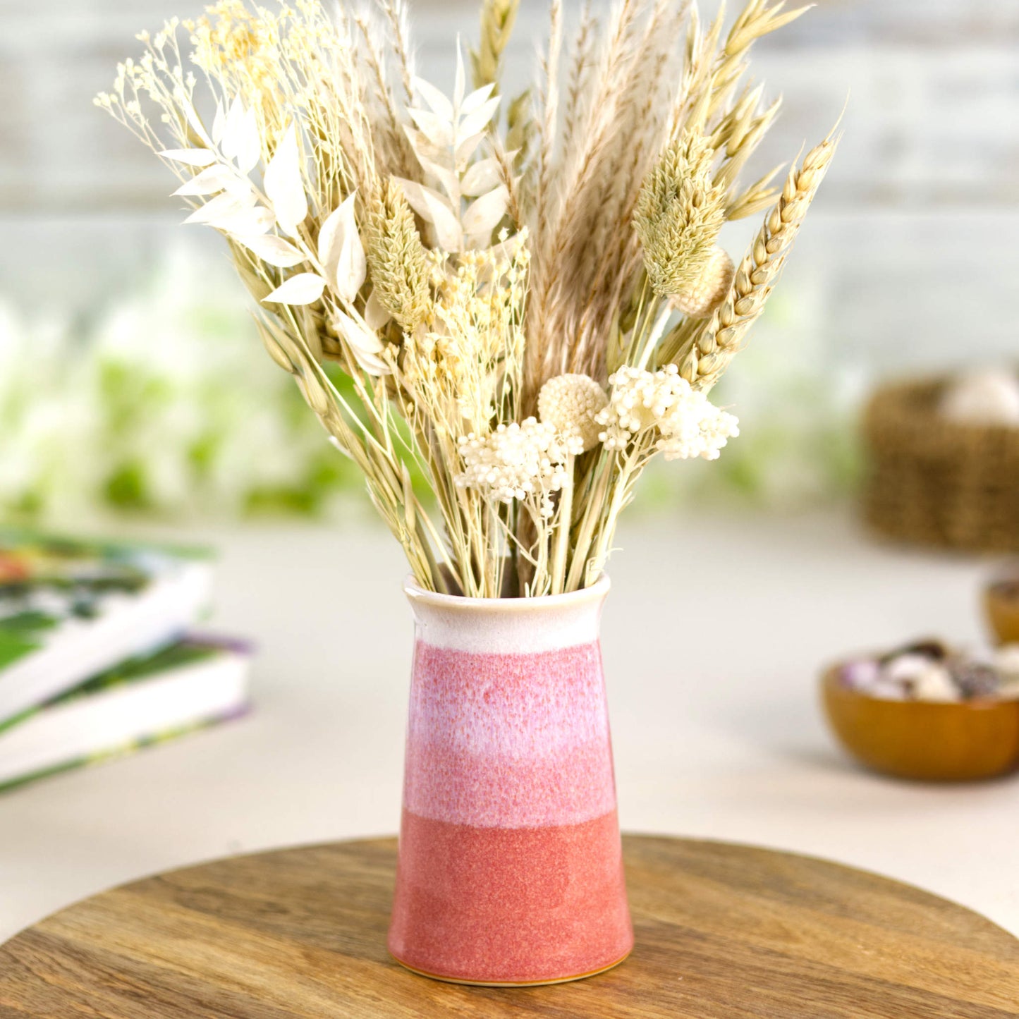 Blush coral and white handmade bud vase with neutral dried grasses, artisan British studio pottery with a striped double-dipped finish.