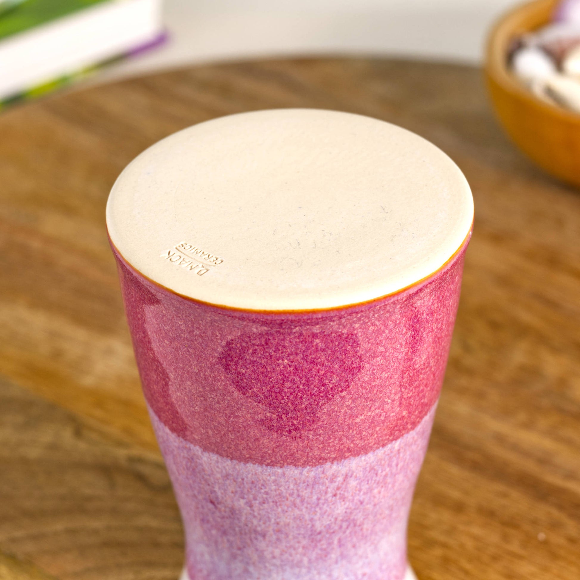 Handmade tapered ceramic bud vase in crimson and white, featuring a two-tone glazed finish, smooth burnished base, and artisan maker’s mark on the underside.