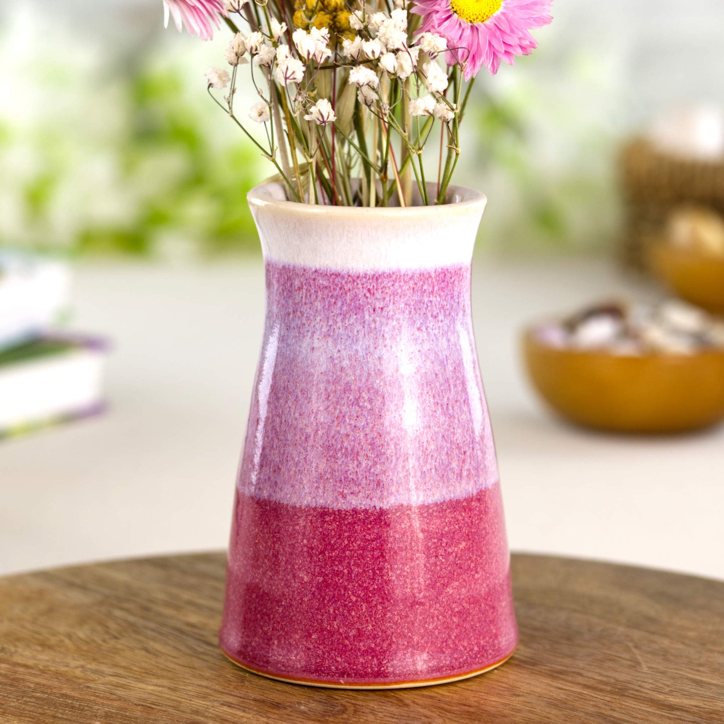 Small tapered ceramic bud vase in rich crimson and ivory white, featuring layered glaze bands, a glossy white rim, and a warm, homely aesthetic on a rustic wooden board.