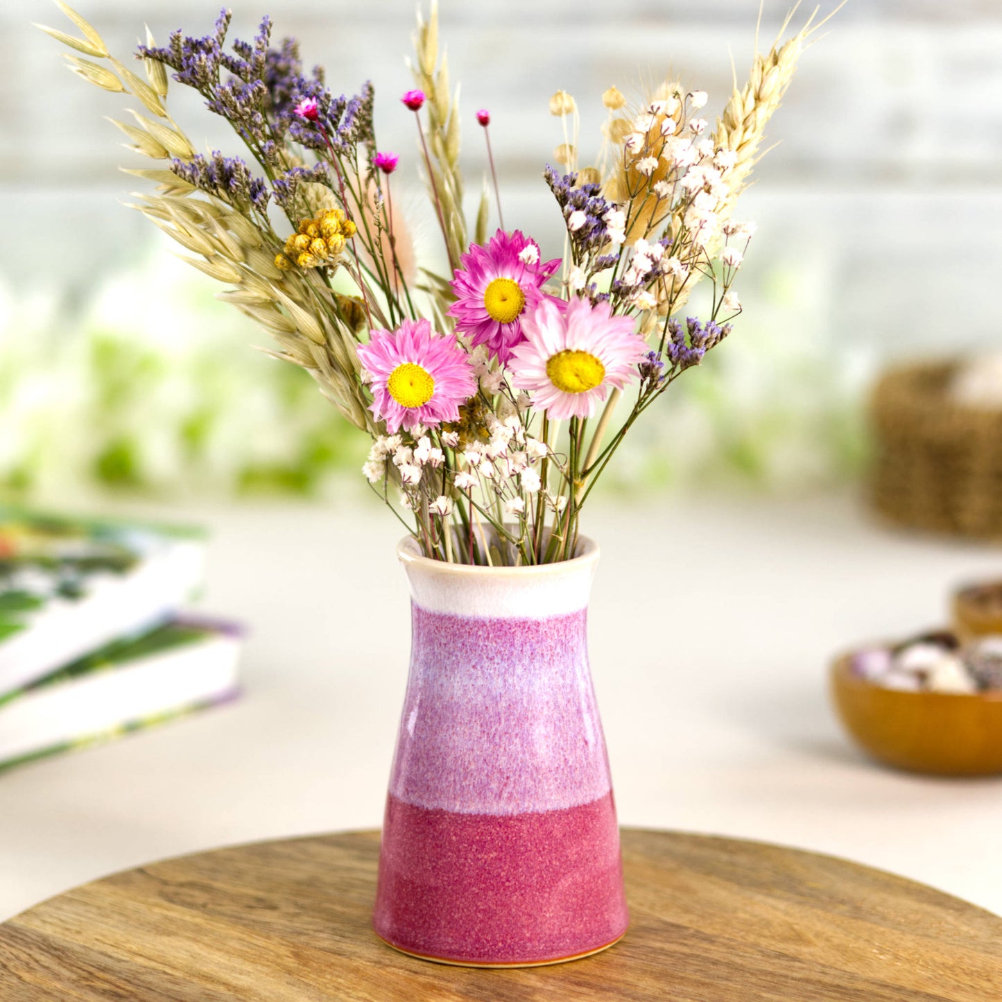 Handmade two-tone bud vase in crimson and white filled with colourful dried flowers, highlighting its elegant tapered shape and decorative striped glaze effect.