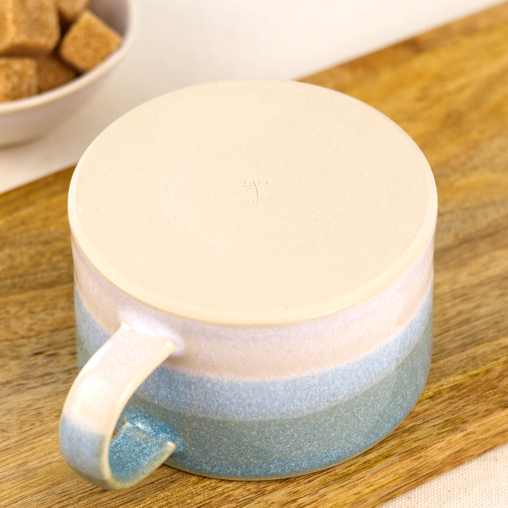 Base of handmade stoneware cappuccino cup with smooth flat underside and maker’s mark, blue and white pottery mug