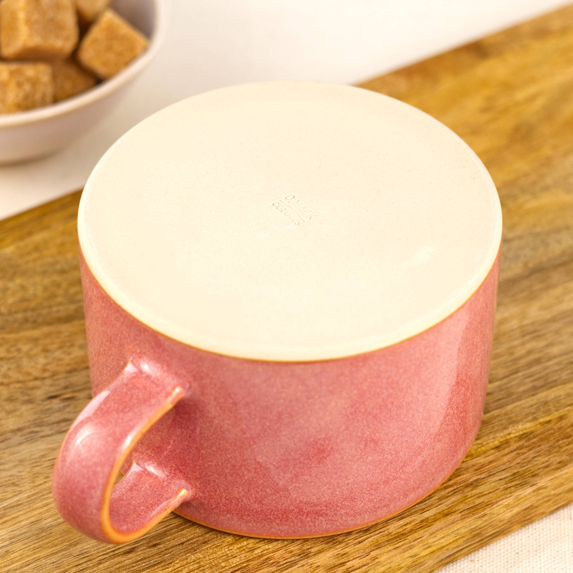 Flat base of handcrafted coral cappuccino cup with maker’s mark, burnished smooth stoneware underside for scratch-free countertops