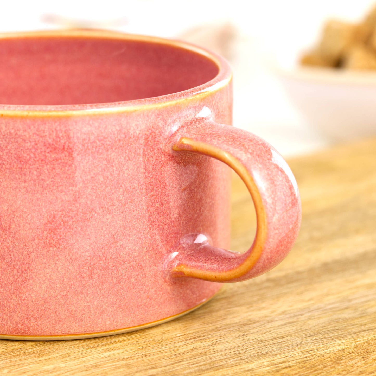Close detail of coral Sea Smoothed Pebble glaze on handmade cappuccino mug, glossy pottery finish in sun warmed tones