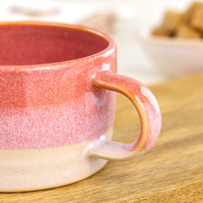 Close view of coral glaze flowing into white on handcrafted cappuccino cup, glossy speckled Sea Smoothed Pebble finish