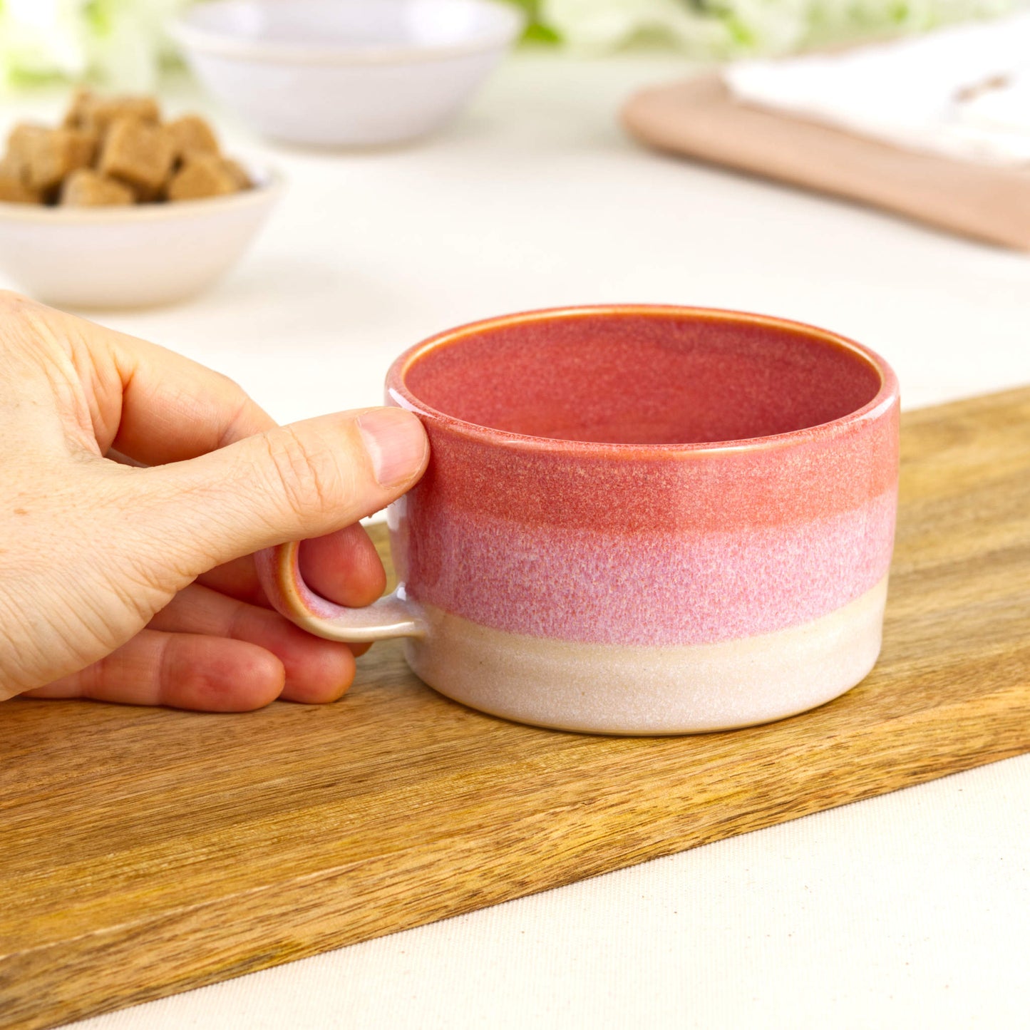 Coral and White ceramic coffee cup held in hand, wheel-thrown cappuccino mug with low wide café style shape