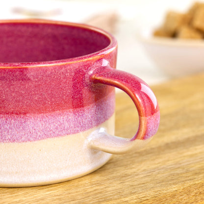 Close view of rich crimson glaze blending into white on handcrafted cappuccino cup, glossy speckled studio pottery finish