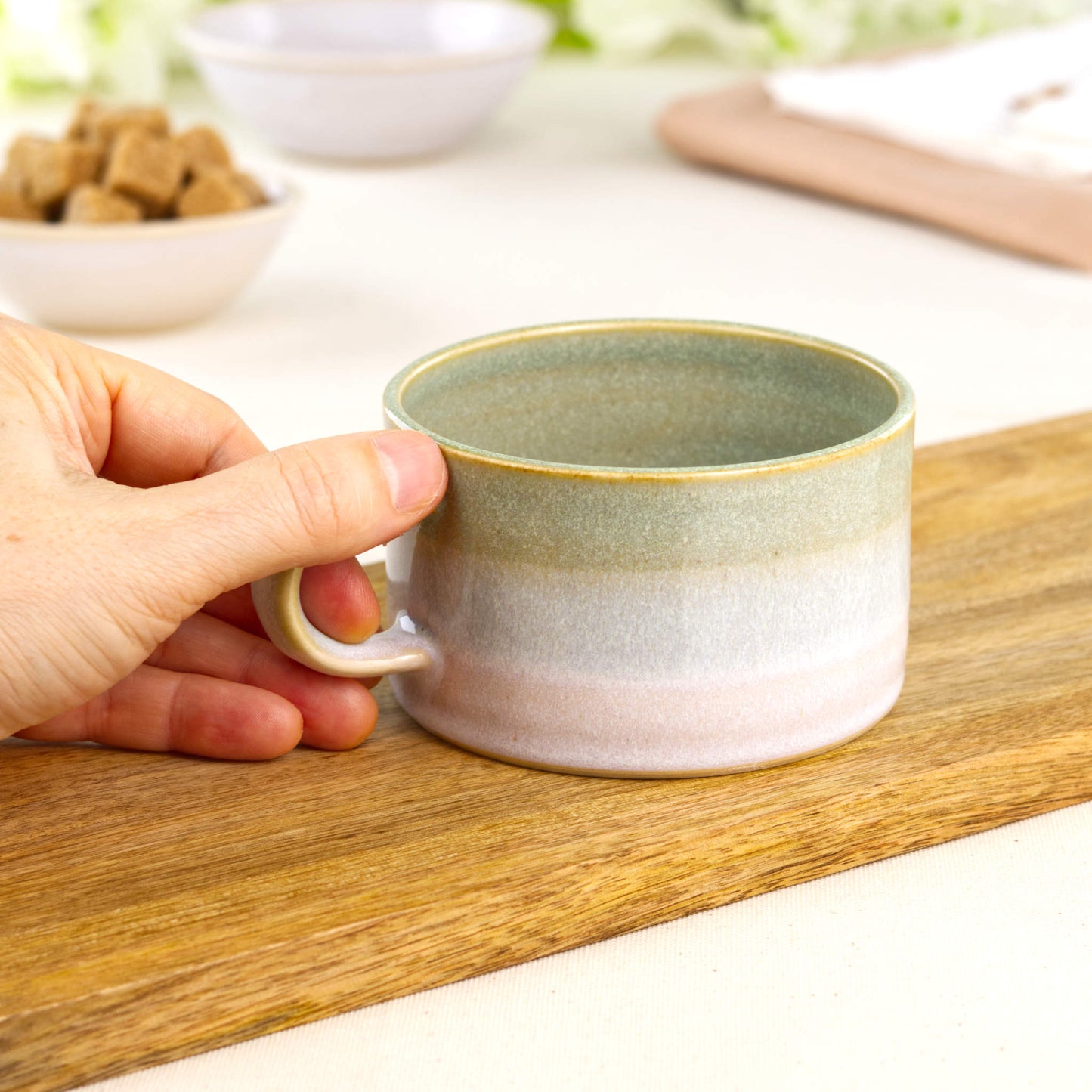 Wheel-thrown Pale Green and White coffee cup held in hand, low wide ceramic cappuccino mug with modern café shape