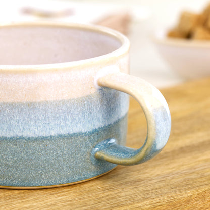 Close view of white glaze flowing into Coastal Blue on handcrafted cappuccino cup, glossy speckled Sea Smoothed Pebble finish