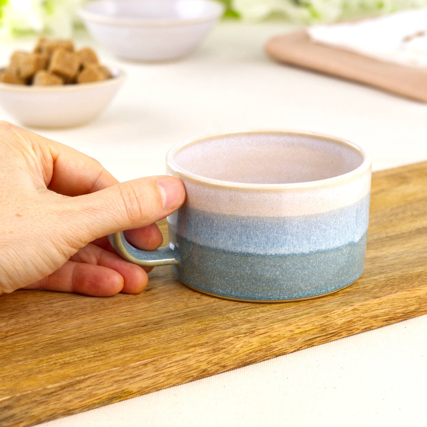 White and Coastal Blue ceramic coffee cup held in hand, wheel-thrown cappuccino cup with wide café style shape