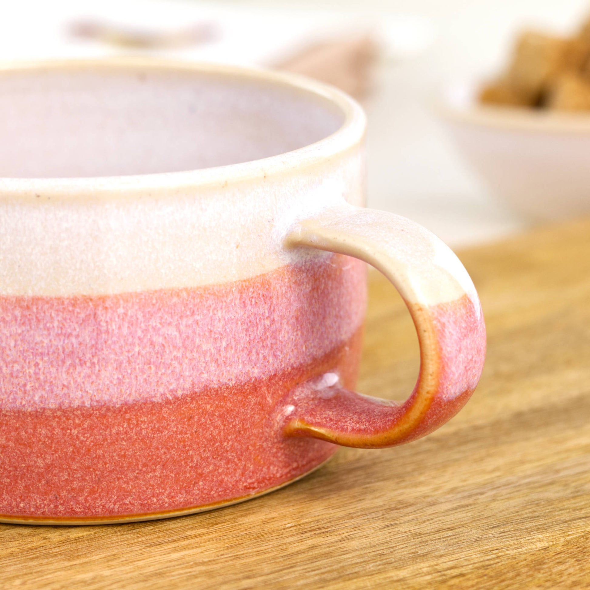 Detail of white glaze melting into warm coral on handmade cappuccino mug, glossy Sea Smoothed Pebble ceramic finish