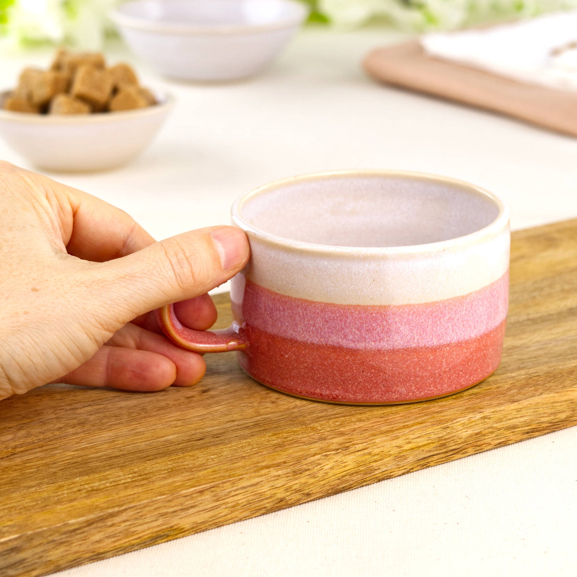 White and Coral pottery coffee cup shown in hand, wheel-thrown café mug with broad rim and comfortable shape