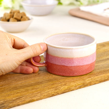 White and Coral pottery coffee cup shown in hand, wheel-thrown café mug with broad rim and comfortable shape