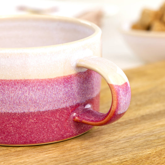 Detail of white glaze blending into deep crimson on handmade cappuccino cup, overlapping glazes