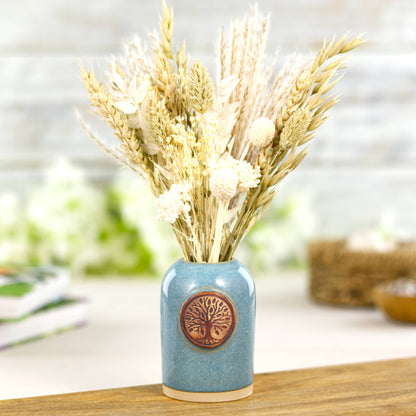 Coastal blue ceramic bud vase or fragrance vessel with dried flowers on wooden plinth