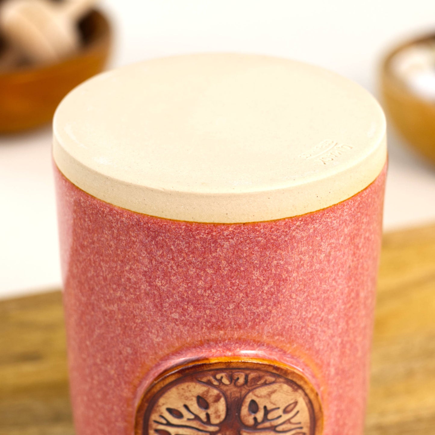 Base of handmade coral ceramic diffuser vessel showing smooth unglazed stoneware foot and maker mark