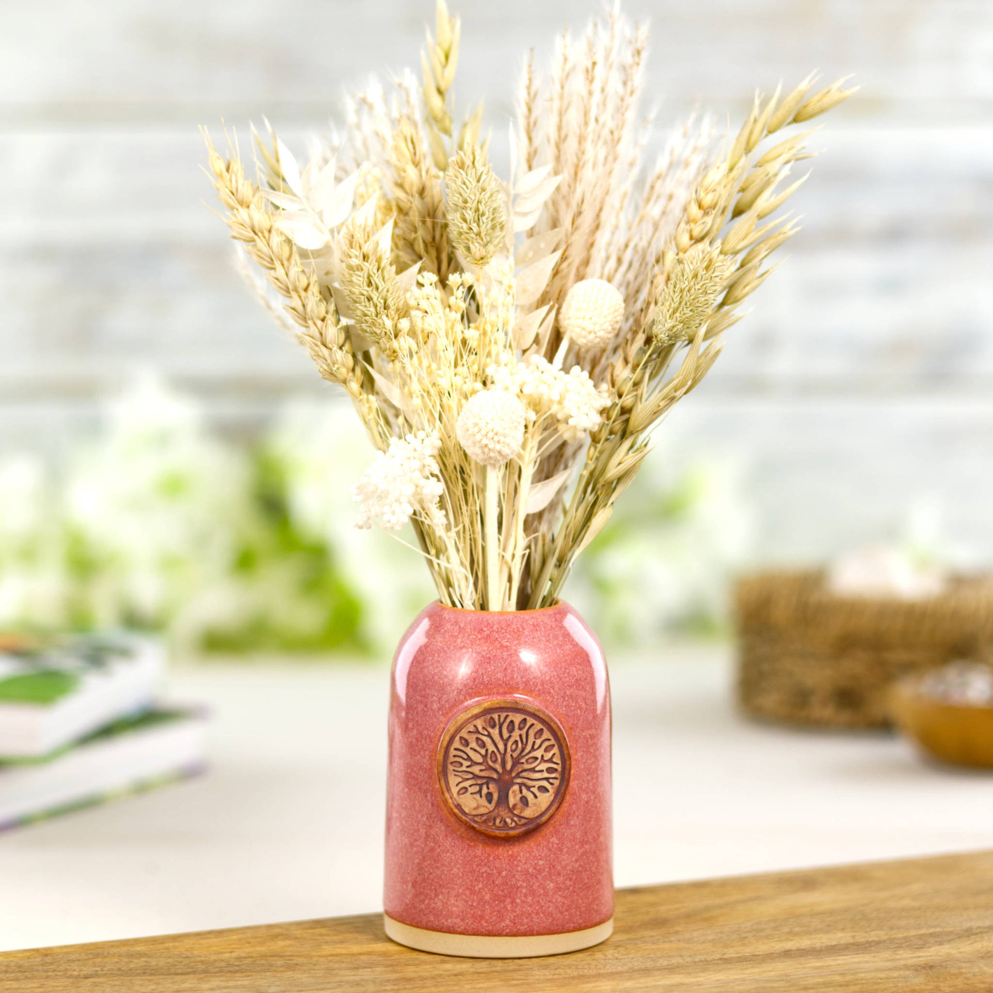 Coral ceramic bud vase with dried flowers in warm sunset tones and nature inspired badge