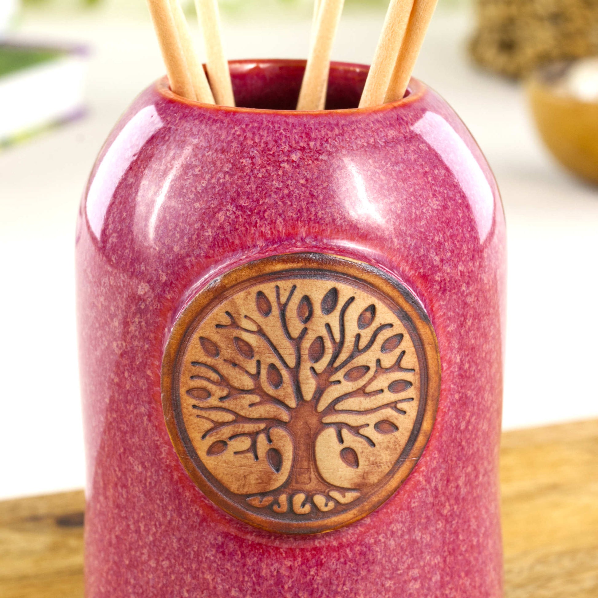 Close up of crimson fragrance diffuser with Tree of Life applique and glossy mottled red glaze