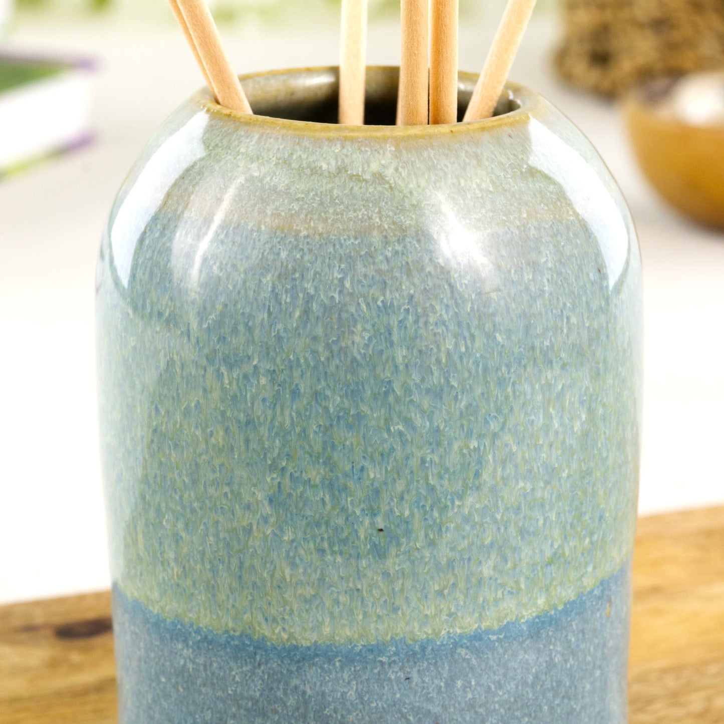 Wheel-thrown stoneware reed diffuser in Coastal Blue and Pale Green with glossy speckled glaze, layered colour bands and rounded neck detail