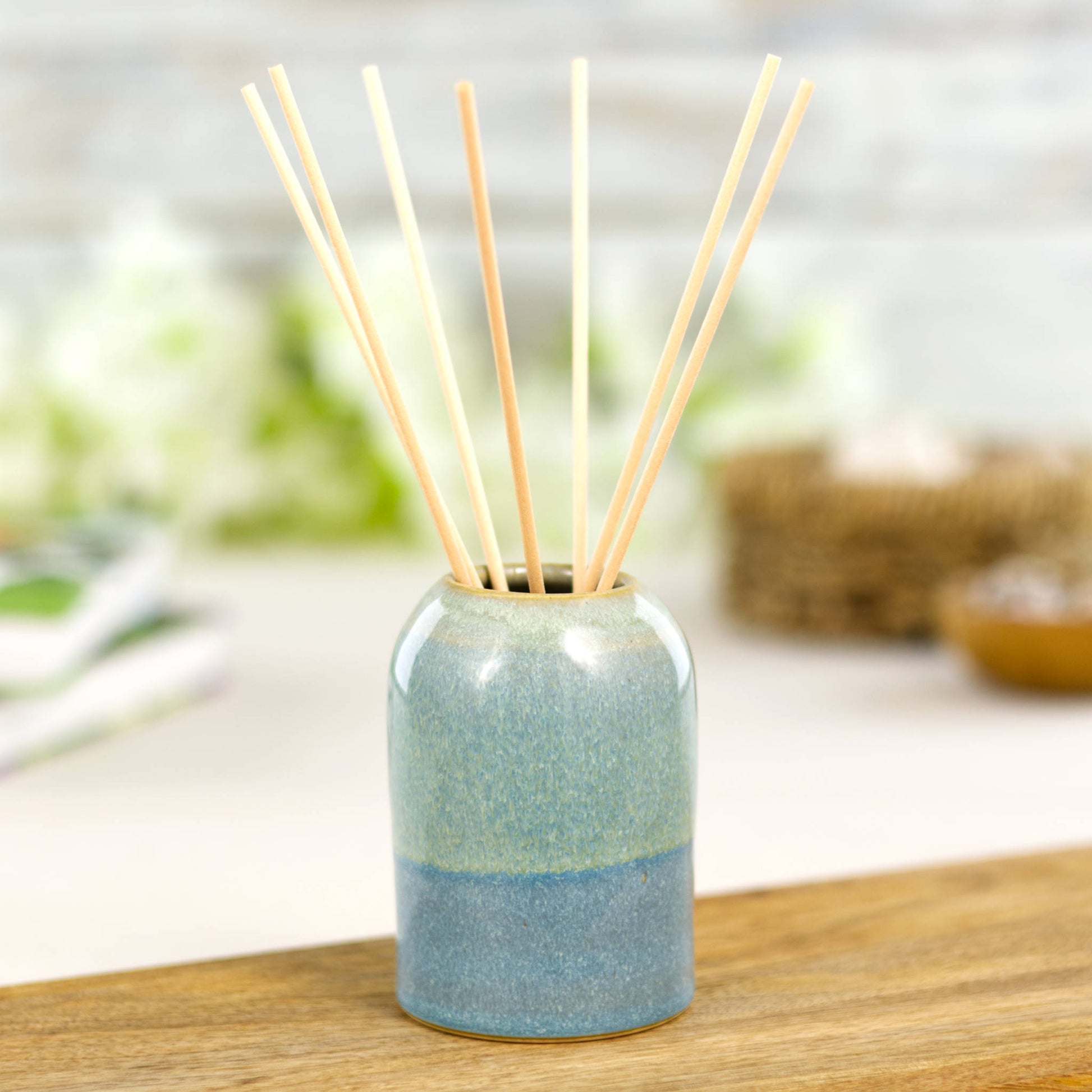 Small wheel-thrown reed diffuser in Coastal Blue and Pale Green with natural fibre reeds, handmade home scent bottle for calming interiors