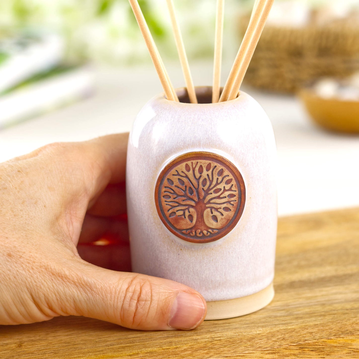 Small handmade white ceramic scent diffuser shown in hand for size with minimalist home decor styling