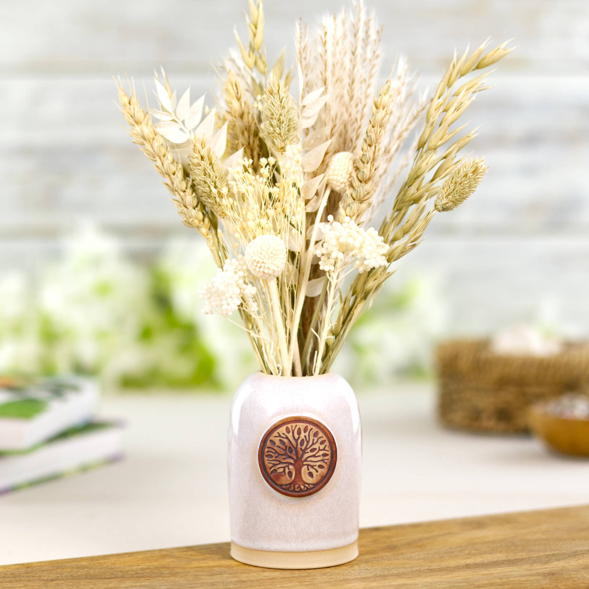 White ceramic bud vase with dried flowers in cottagecore arrangement and rustic natural styling