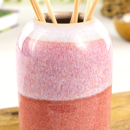 Close-up of layered flowing coral and white glazes on a ceramic reed diffuser with glossy speckled finish - Sea Smoothed Pebble glaze