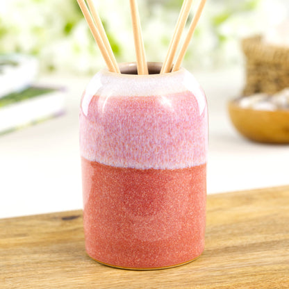 Warm Coral and White stoneware reed diffuser with modern rounded form on wooden surface