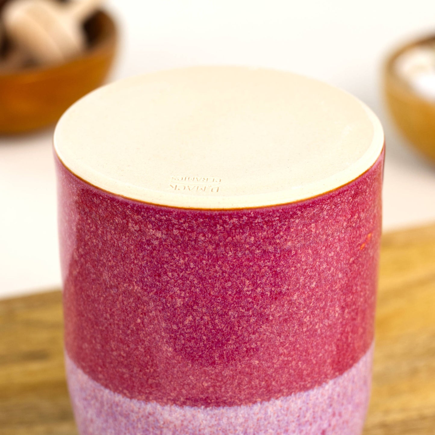 Handmade crimson and white ceramic reed diffuser base with smooth unglazed foot on wooden shelf