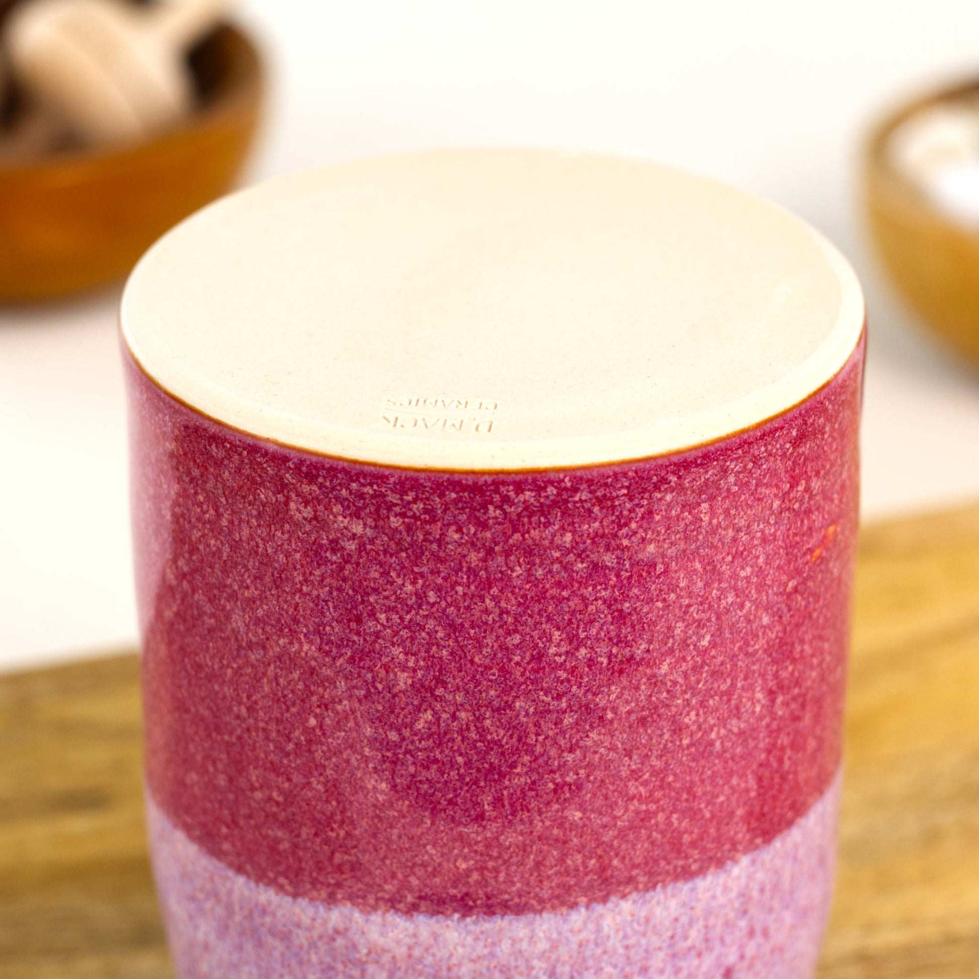 Handmade crimson and white ceramic reed diffuser base with smooth unglazed foot on wooden shelf