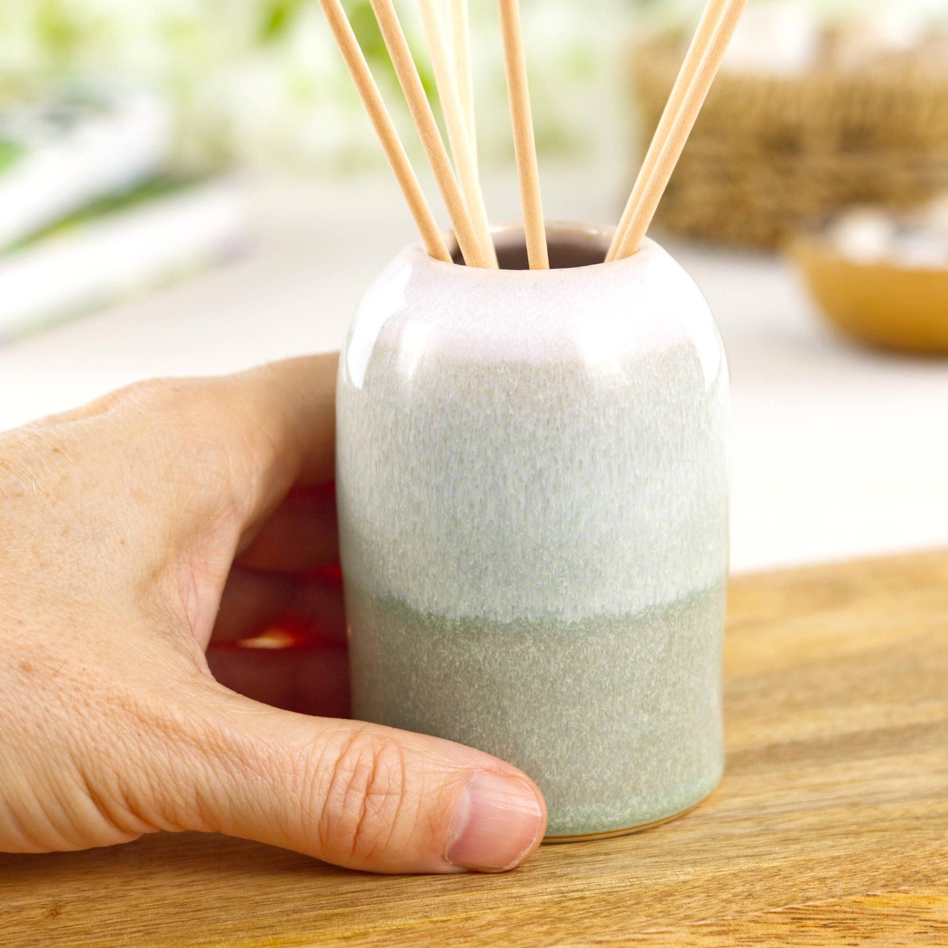 Small Pale Green and White handmade home fragrance pot shown in hand for size, compact pottery decor piece