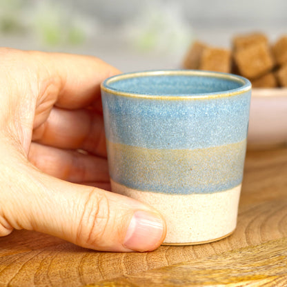 Wheel-thrown stoneware espresso cup in hand showing small coffee size and layered glaze finish