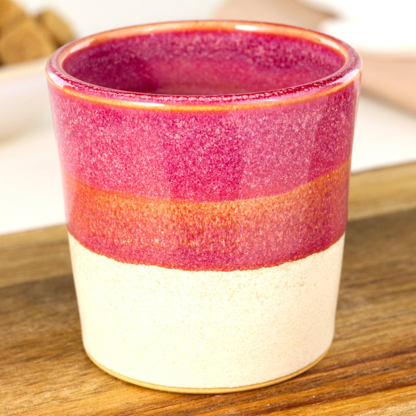 Handmade banded espresso cup close-up showing deep crimson glaze and satin matte sandy base